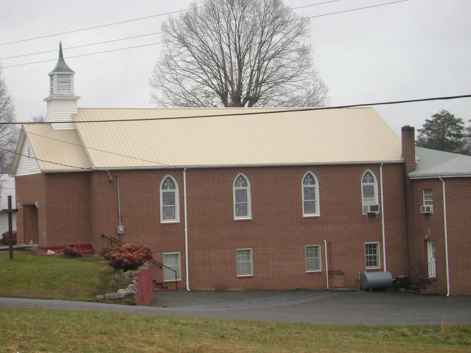 New tan metal roof on a brick church with a white steeple in Linwood